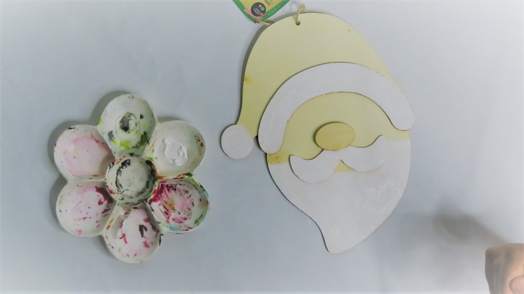 Paint Santa's beard, and the puffball and trip on his hat with white acrylic craft paint | How to Turn a Dollar Tree Santa Head into a Masterpiece