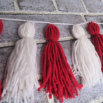 Completed tassel garland against a gray brick background | Make Your Own Tassel Garland