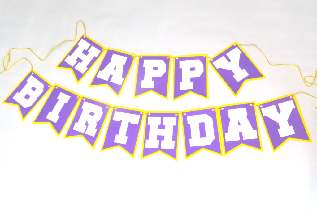 DIY Happy Birthday Banner. The banner is purple with white letters and a yellow border | 5 Amazing Football Party Decorations