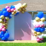 white and pink DIY Chiara Backdrop with a pink, blue, white, and gold balloon garland attached and a balloon column on the side