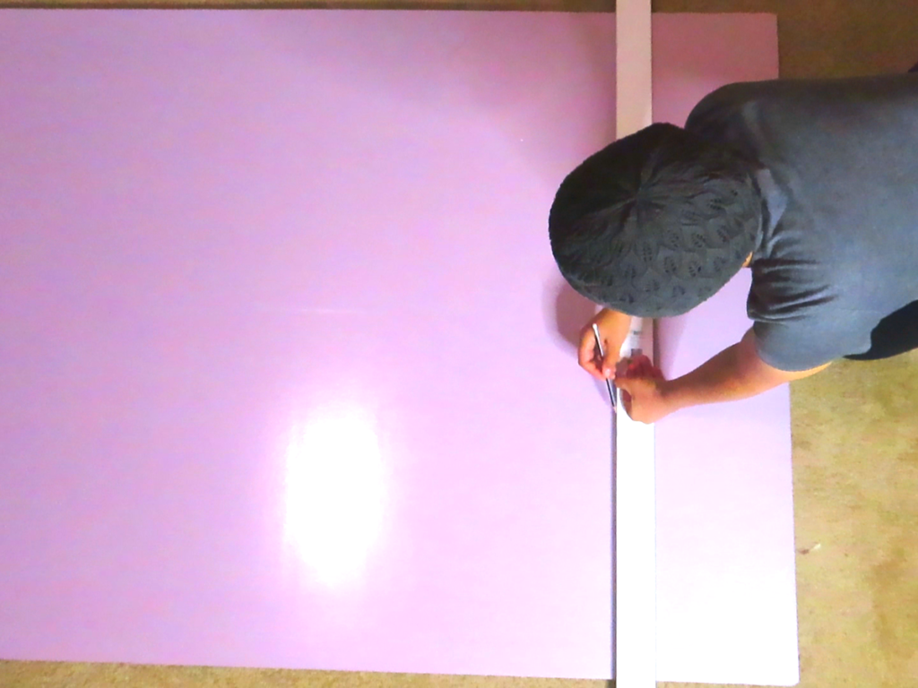 Drawing a line across an insulation board using a yard stick