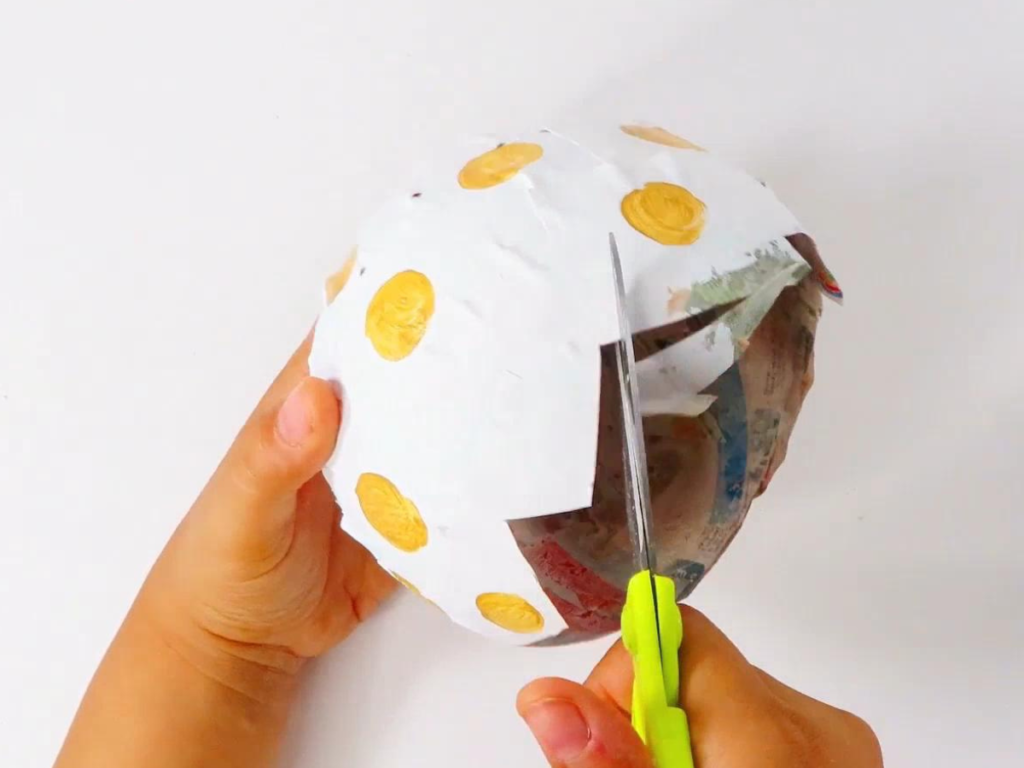 Cut a zig zag pattern into the opening of the paper mache dinosaur egg