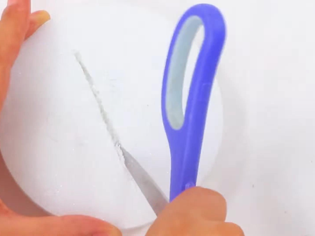 Carving a line into the foam disk with a pair of scissors