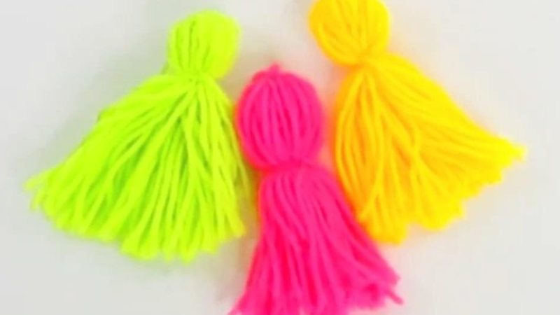 This image shows three handmade tassels laying beside each other. From left to right, the first is lime green, the second is pink, and the third is yellow.
