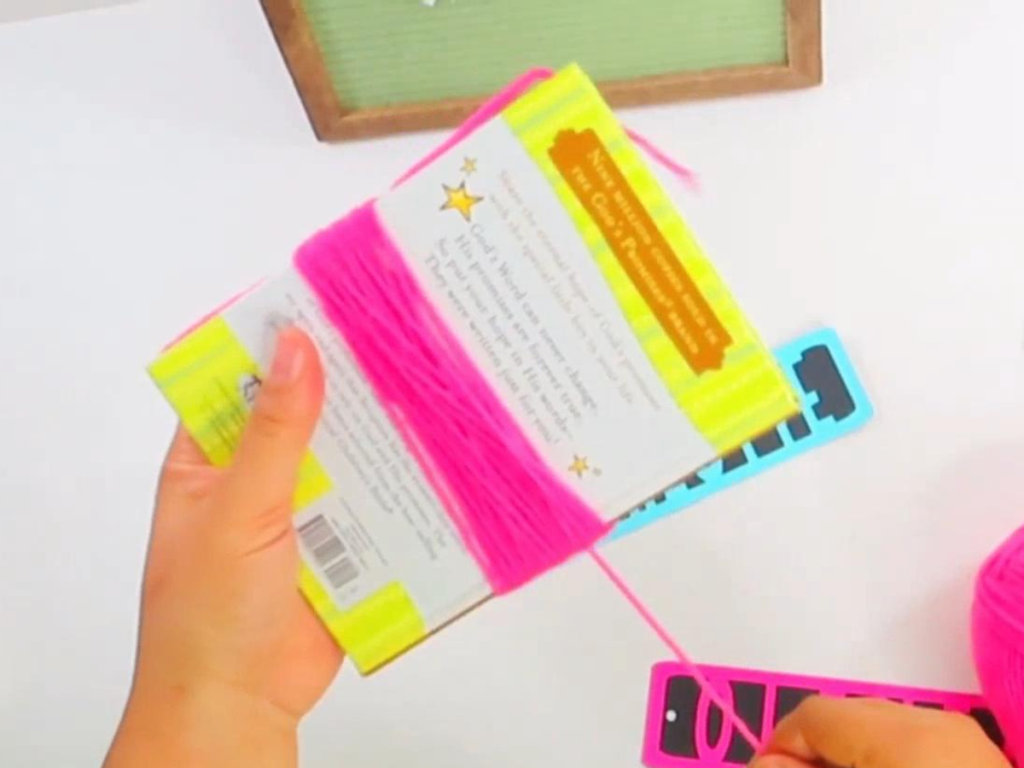 This image shows bright pink yarn wrapped around a small book 33 times.