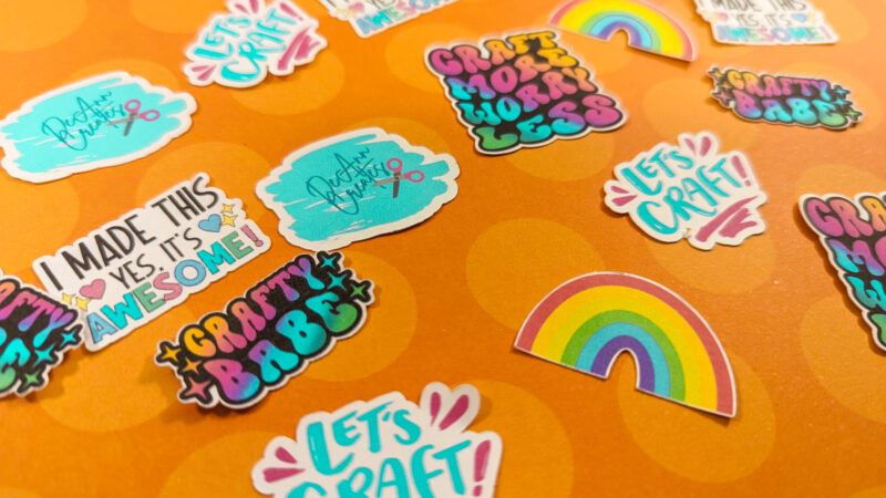 This image shows DIY colorful stickers laying on and orange surface | Photo by DeAnn Creates | How to Make Stickers with Cricut: Crafting Made Easy