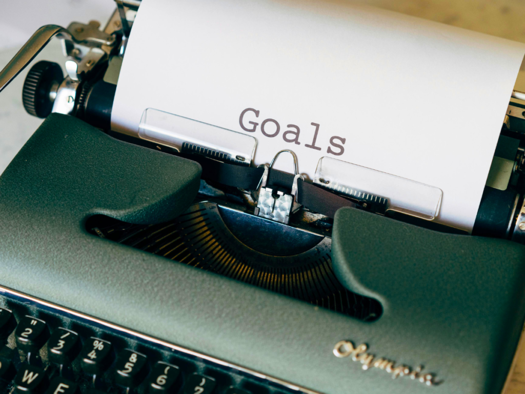 This image shows a typewriter with a sheet of paper inside that has the word "Goals" typed on it. | 3rd Anniversary of DeAnn Creates: 3 Years of Crafting Magic | Photo by Markus Winkler