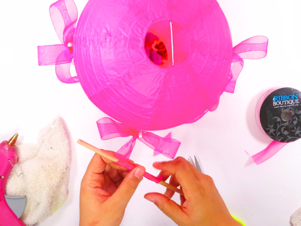 This image shows a pair of hands curling the end of the ribbon with cake topper sticks | How to Make a Stunning Hot Air Balloon Centerpiece for Any Occasion