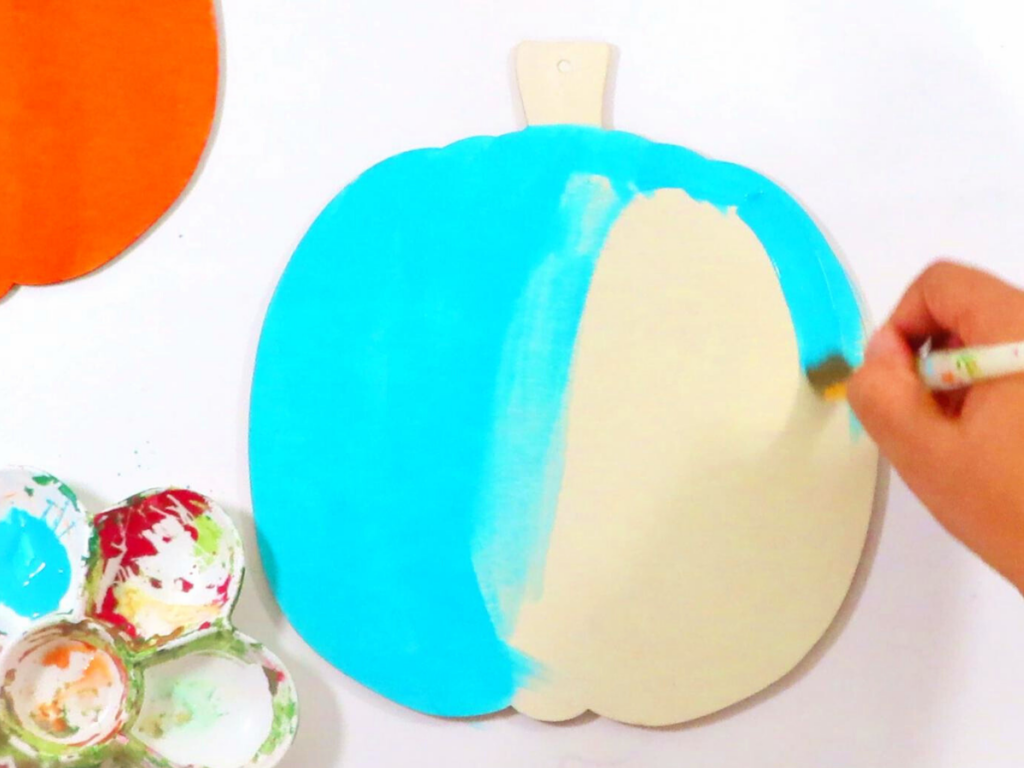 Painting a wooden pumpkin with the paint color Aqua by Craftsmart | DIY Fall Decor You'll Love Making with Simple Decor